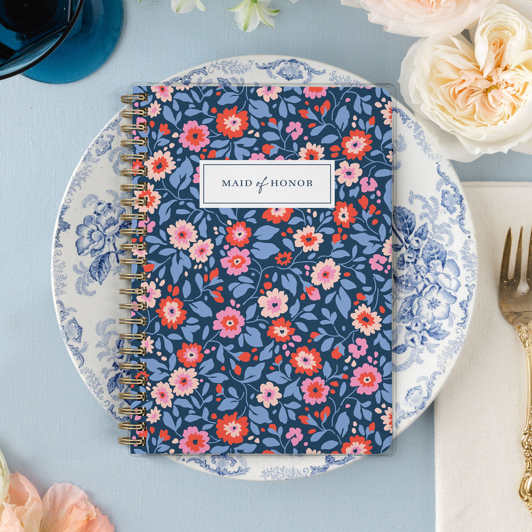 Our exclusive maid of honor planners are the perfect gift for your best friend, shown in a preppy red, pink and navy floral design.